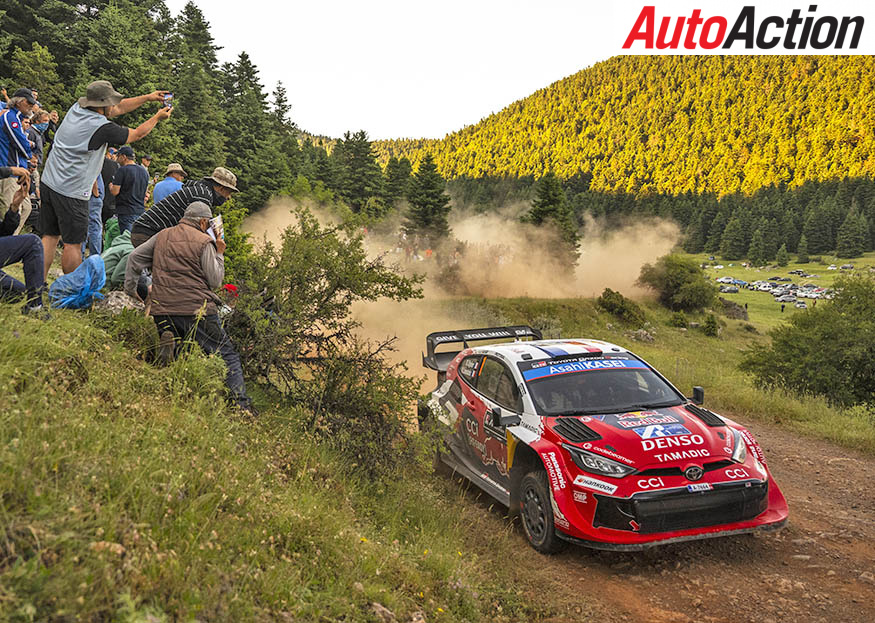 Sebastien Ogier driving the red Toyota GR Yaris Rally1 on a gravel stage as spectators and photographers watch from the bank at the 2026 Acropolis Rally.