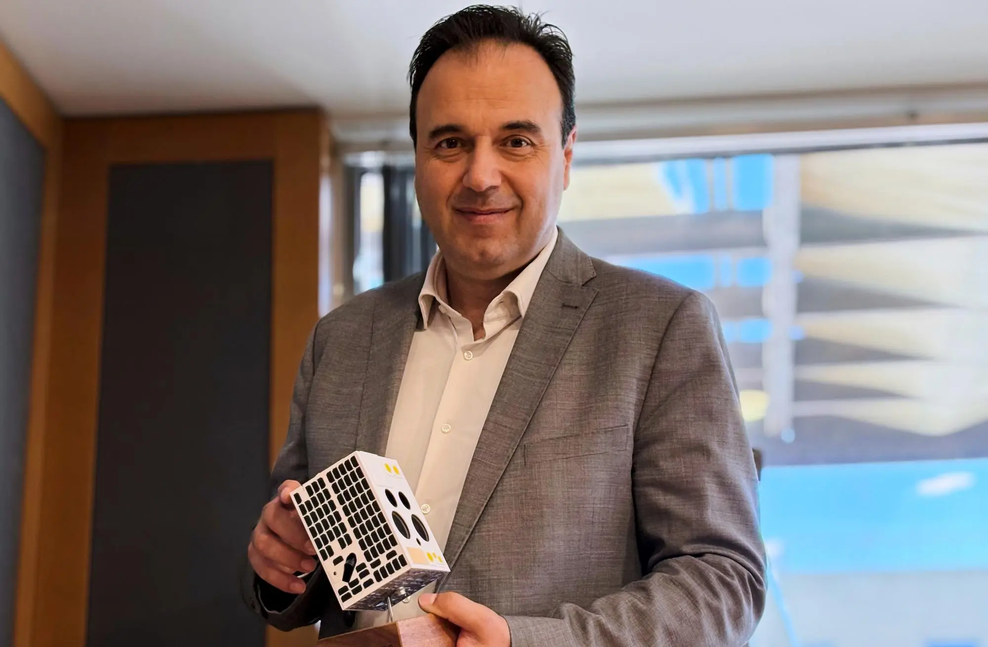 Dijital Yönetişim Bakanı Dimitris Papastergiou, bir nano uydu maketiyle poz veriyor. (AP Fotoğraf/Lefteris Pitarakis)