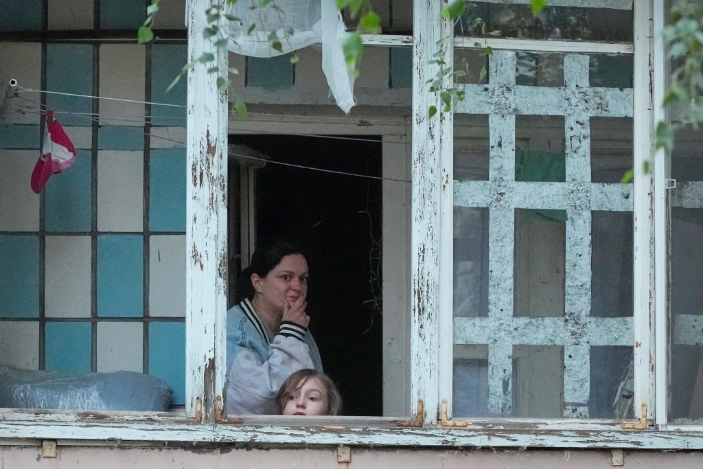 Yerel sakinler, Kiev'deki Rus füze saldırısında hasar gören bir binanın balkonundan bakıyor.