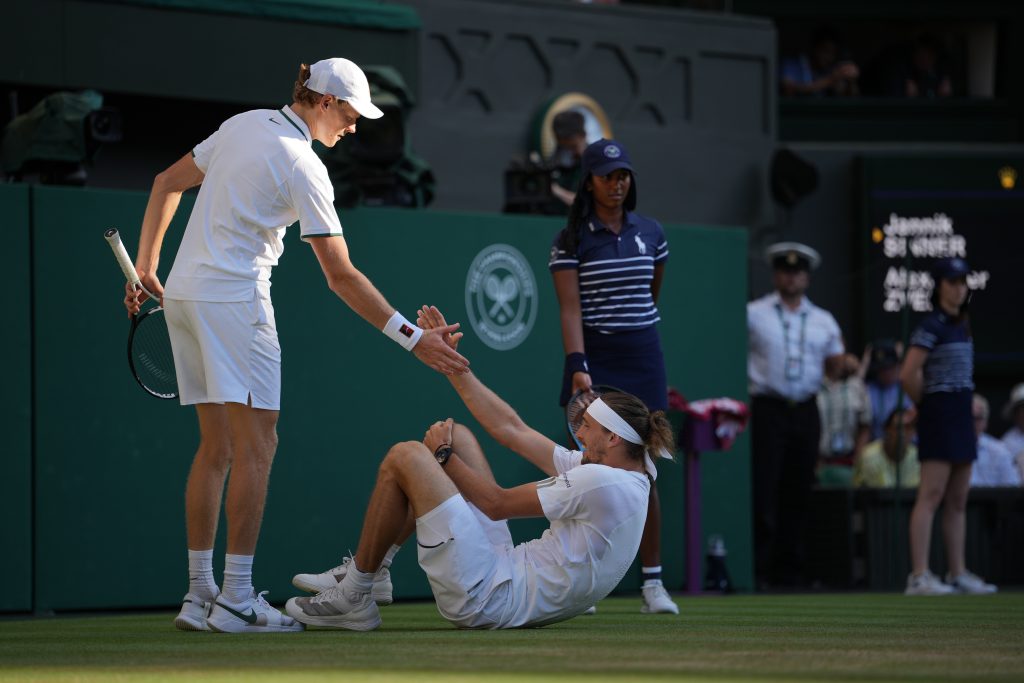 Jannik Sinner of Italy, left helps up Alexander Zverev of Germany who fell during the men's singles final at Wimbledon Tennis Championships in London, Sunday, July 12, 2026. (AP Photo/Kin Cheung)