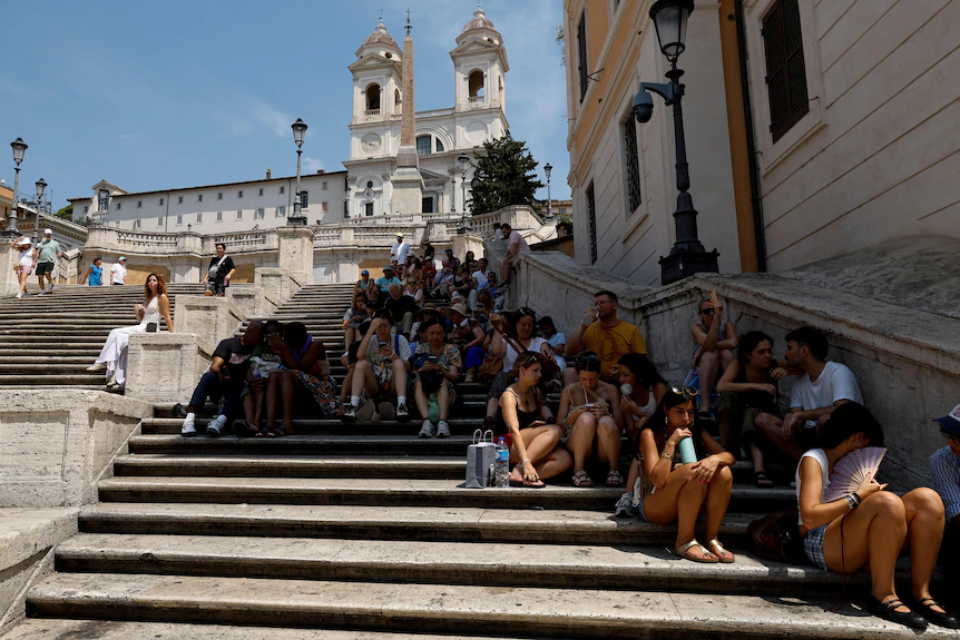 Roma'da bir merdivende birkaç düzine turist gölgede toplanmış.
