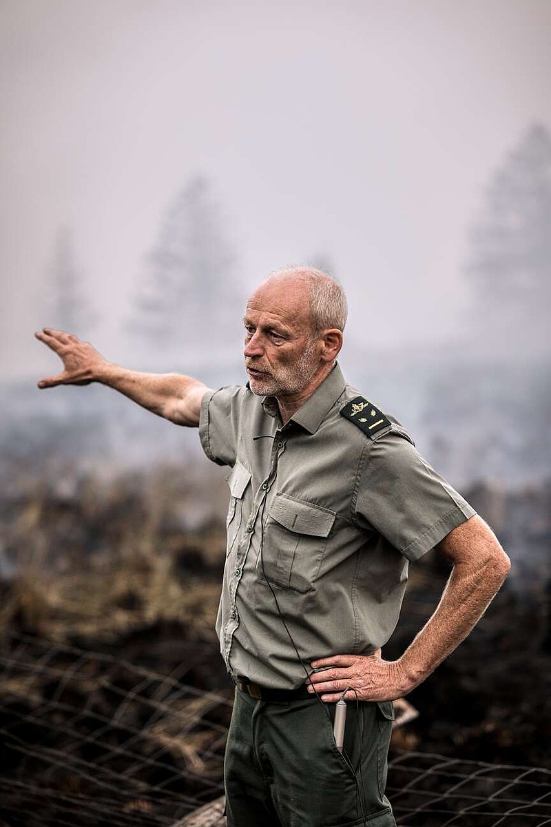District Forestry Officer of the Haute Fagnes, Yves Pieper, speaks with the media as smoke rises from a field and forest as a wildfire burns near Waimes, Belgium, Monday, Aug. 17, 2026. (AP Photo/Valentin Bianchi)
